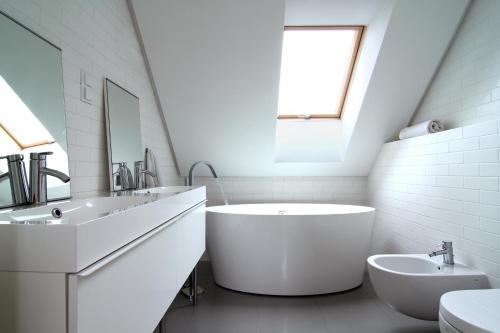 a white bathroom with a large tub and a sink at Osada Osjaków in Osjaków