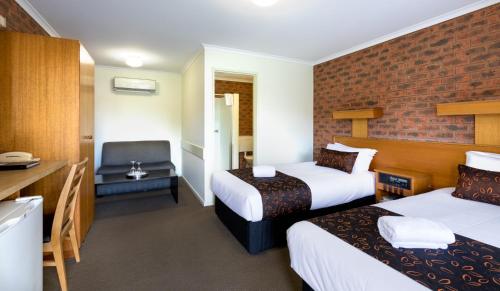 a hotel room with two beds and a desk at Advance Motel in Wangaratta