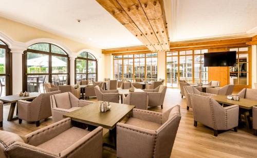 um restaurante com mesas, cadeiras e janelas em Wellnesshotel ...liebes Rot-Flüh em Haldensee