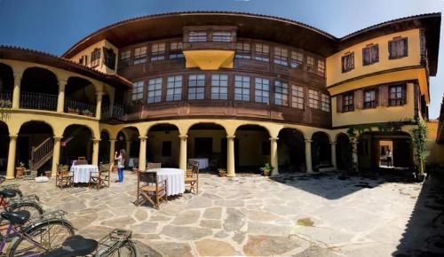 un grand bâtiment avec des tables et des chaises dans une cour dans l'établissement Anemon Hotel Kula, à Kula