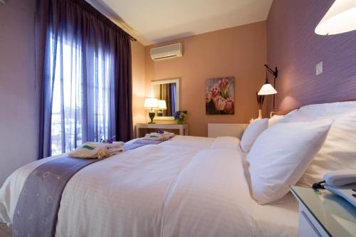 a bedroom with a large white bed with a window at Nikoleta Hotel and Villas in Limenas