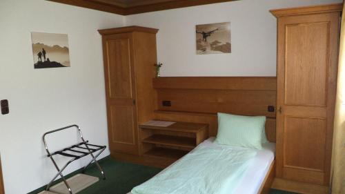 a small bedroom with a bed and a chair at Gästehaus Tramnitz in Mayrhofen