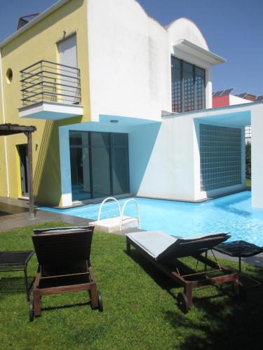 a house with two chairs and a swimming pool at Coin de paradis in Quinta do Anjo