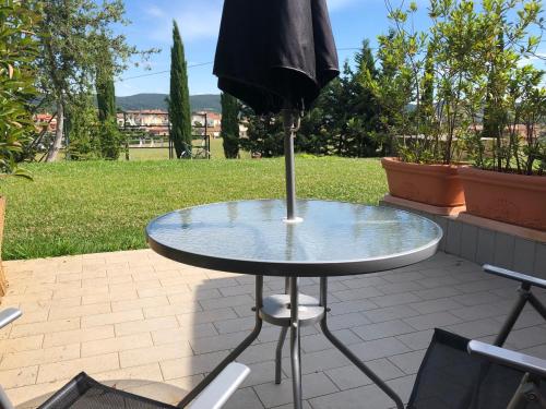 a glass table with an umbrella on a patio at La Locanda della Vecchia Hosteria in Gavorrano