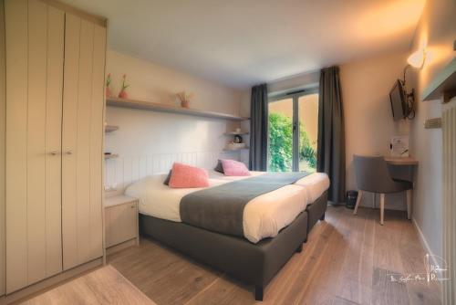 a bedroom with a bed with pink pillows on it at Hotel Bilderdijk in De Haan