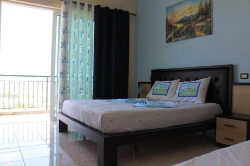 - une chambre avec un lit et une porte coulissante en verre dans l'établissement Hotel Aleksandrus Jardin, à Durrës