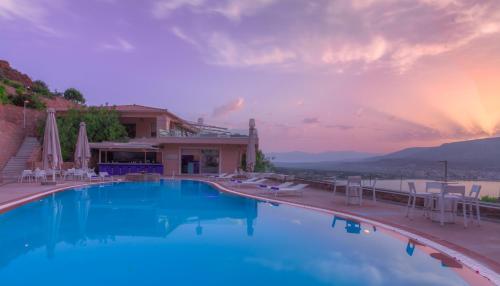 a large swimming pool with chairs and a building at Princess Kyniska Suites in Plytra