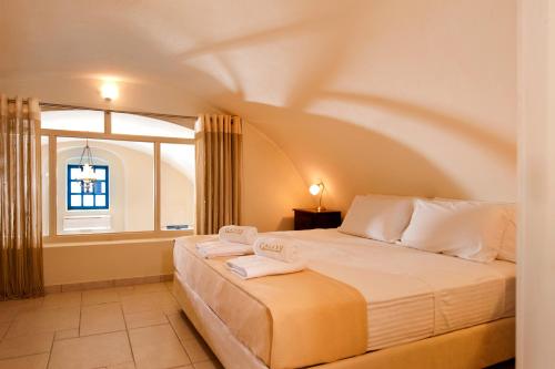 a bedroom with a large bed with a window at Galaxy Suites & Villas in Imerovigli