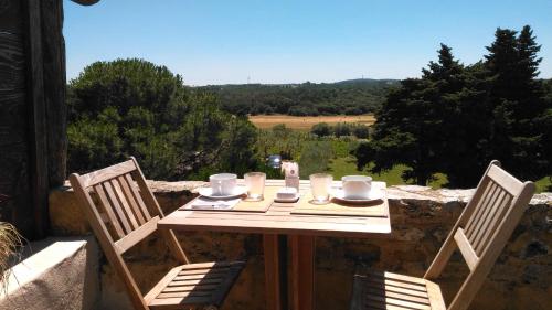 a wooden table with two chairs and a table with cups at Esprit Garrigues d'Uzès in Pougnadoresse