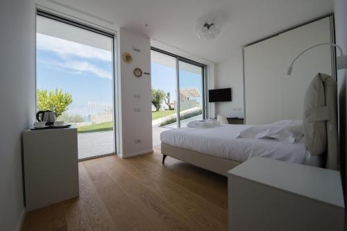 a white bedroom with a bed and a large window at B&B Capo Torre Resort & SPA in Albisola Superiore