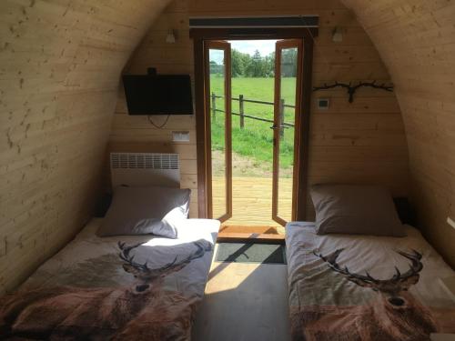 2 Betten in einem kleinen Zimmer mit Fenster in der Unterkunft De Rozephoeve Studio in Oisterwijk