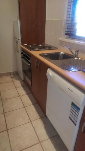 a kitchen with a sink and a stove and a refrigerator at Country Plaza Motel in Queanbeyan