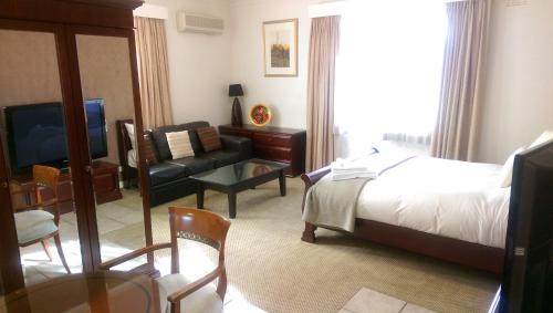 a bedroom with a bed and a couch and a television at Country Plaza Motel in Queanbeyan