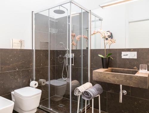 y baño con ducha, aseo y lavamanos. en Shalai Relais Apartment, en Pachino
