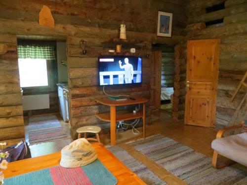 a living room with a television in a log cabin at Hakamajat Cottages in Syöte