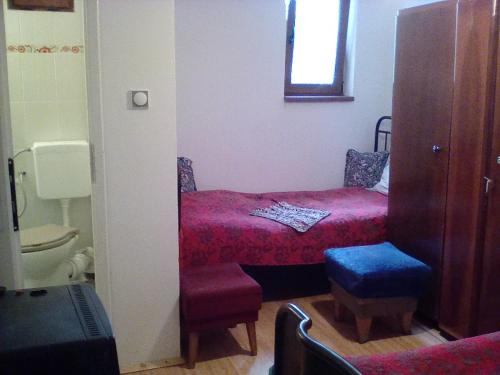 een kleine slaapkamer met een bed en een toilet bij Екологична къща за гости in Kovachevets