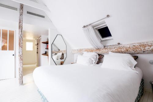 une chambre blanche avec un grand lit et un miroir dans l'établissement Hôtel du Temps Paris, à Paris