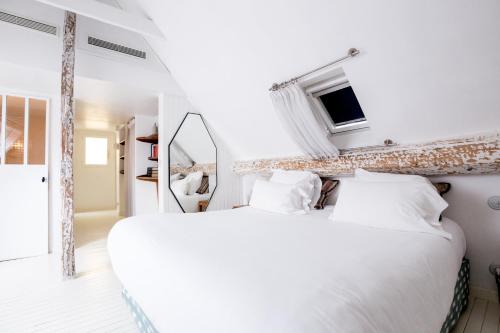 - une chambre blanche avec un grand lit et un miroir dans l'établissement Hôtel du Temps, à Paris