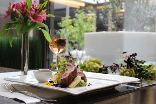 a plate of food and a glass of wine on a table at Ramada Plaza by Wyndham Bucharest Convention Center in Bucharest