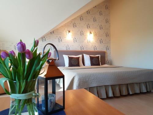 a bedroom with a bed and a vase of flowers on a table at Rasos Vila in Palanga