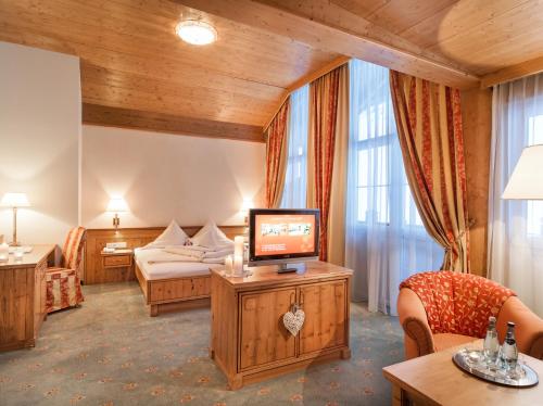 a hotel room with a television and a bed at Hotel Alpenhof Superior in Zauchensee