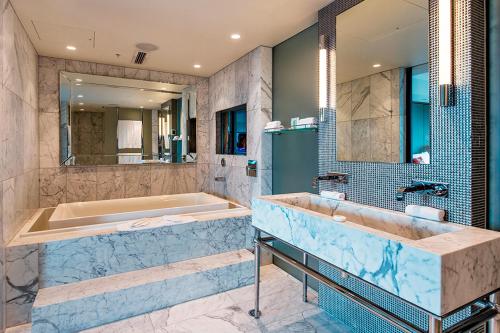 a bathroom with a tub and a sink at The Grand by SkyCity in Auckland