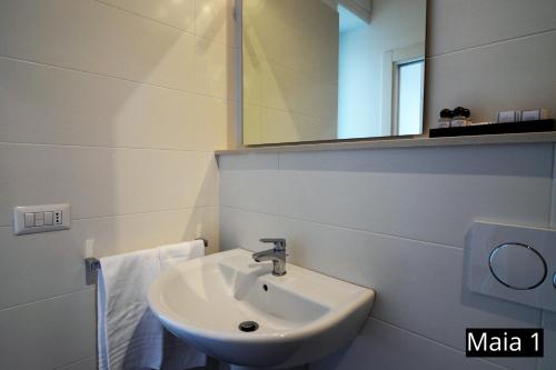 a white bathroom with a sink and a mirror at Case Vacanze Maia in Matera
