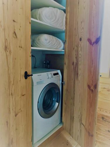 a washing machine in a wooden cabinet with plates at Chalet ELK Lenk in Lenk