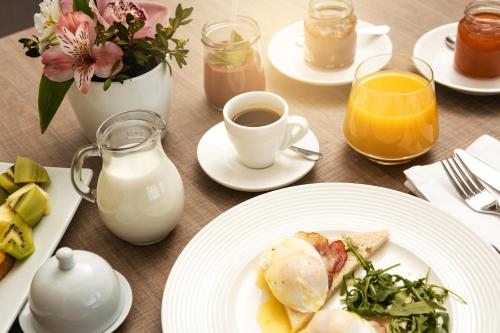 a table with plates of food and a cup of coffee at Ramada Encore Kyiv in Kyiv