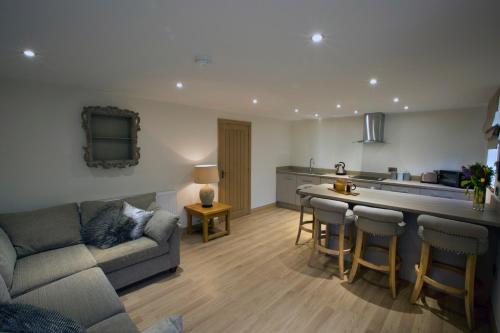 a living room with a couch and a kitchen at Woodspurge Cottage, Drift House Holiday Cottages in Astbury