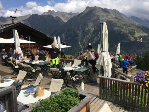 a restaurant with tables and umbrellas with mountains in the background at Alpenspirit in Sölden
