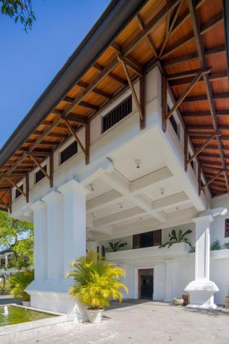 a large white building with a wooden roof at Mahaweli Reach Hotel in Kandy