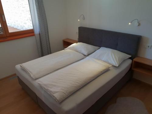 Una cama con sábanas blancas y almohadas en un dormitorio en Appartement De Martin, en Aurach bei Kitzbuhel