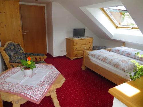 a attic room with a bed and a table with a table sidx sidx at Gästehaus am Berg in Hirschegg