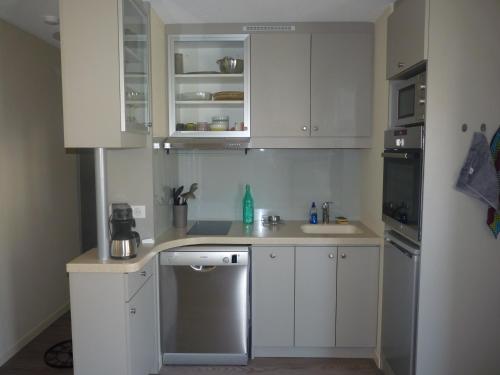 - une petite cuisine avec des placards blancs et un lave-vaisselle dans l'établissement Appartement T3, 5 couchages, Residence La Mediterranee, Narbonne Plage, à Narbonne-Plage
