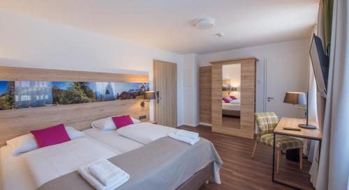 a hotel room with a large bed and a desk at Stücklhof Eurasburg in Eurasburg