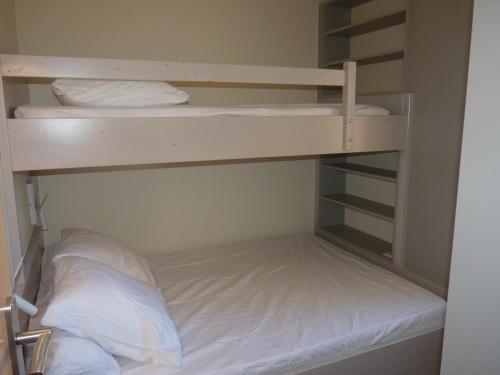 - un lit superposé avec des draps blancs et des oreillers dans l'établissement Appartement T3, 5 couchages, Residence La Mediterranee, Narbonne Plage, à Narbonne-Plage