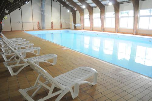 - une grande piscine bordée de chaises longues blanches dans l'établissement Village Vacances Passion Georges Moustaki, à Les Moussières