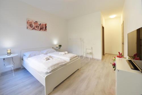 a white bedroom with a white bed and a table at Mary's Rooms & Apartments in Bolzano