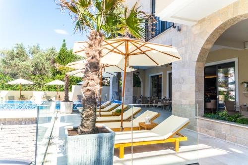 a patio with a palm tree and chairs and an umbrella at B&B Amfora in Petrovac na Moru