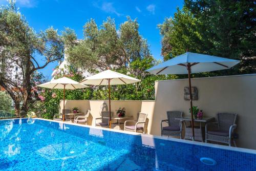 a swimming pool with umbrellas and tables and chairs at B&B Amfora in Petrovac na Moru