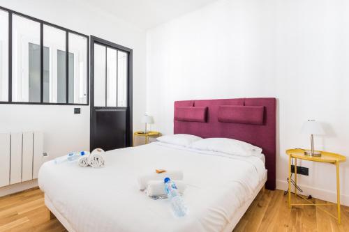 a bedroom with a large white bed with a purple headboard at CMG Saint-Antoine Bastille 6 in Paris