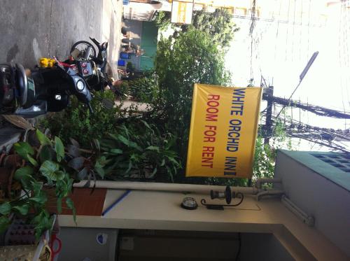 a yellow sign on a desk with plants at White Orchid Inn II in Bangkok