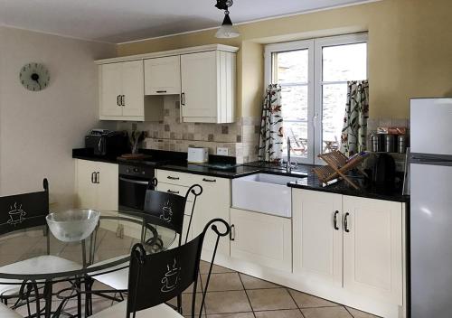 a kitchen with white cabinets and a glass table and a table and a dining room at Val Rive - Brandily Apartment in Dinan
