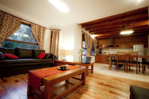 una sala de estar con un sofá y una mesa en Cabañas Bosque del Nahuel, en San Carlos de Bariloche