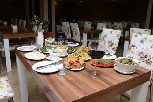 a wooden table with plates of food and a glass of wine at Natali Hotel in Borjomi