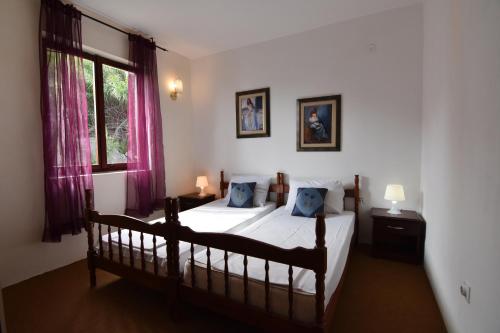 a bedroom with a bed and a window with pink curtains at Vuko i Magdalena Midzor in Petrovac na Moru