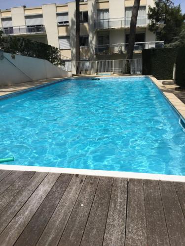 une grande piscine bleue devant un immeuble dans l'établissement Stella le Touquet Berck T2, à Stella-Plage