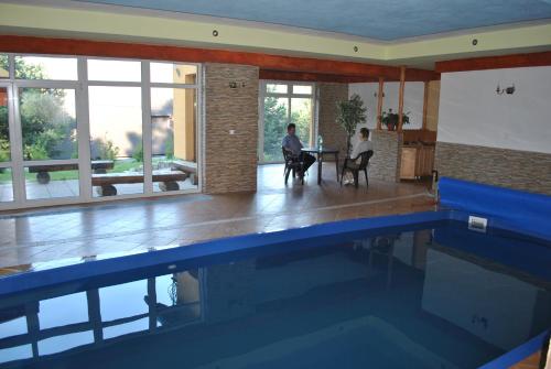 a swimming pool with two people sitting at a table at Penzion Ustie in Trstená
