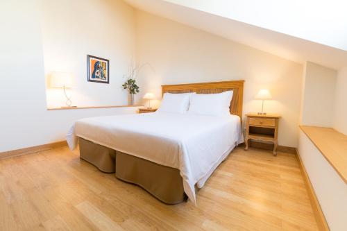 um quarto com uma grande cama branca e piso em madeira em Aguia - T1 By RMC no Funchal